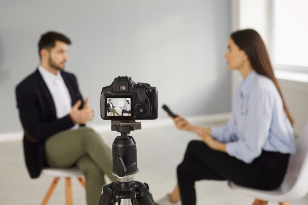 A man undertakes a mock interview with his trainer during media training